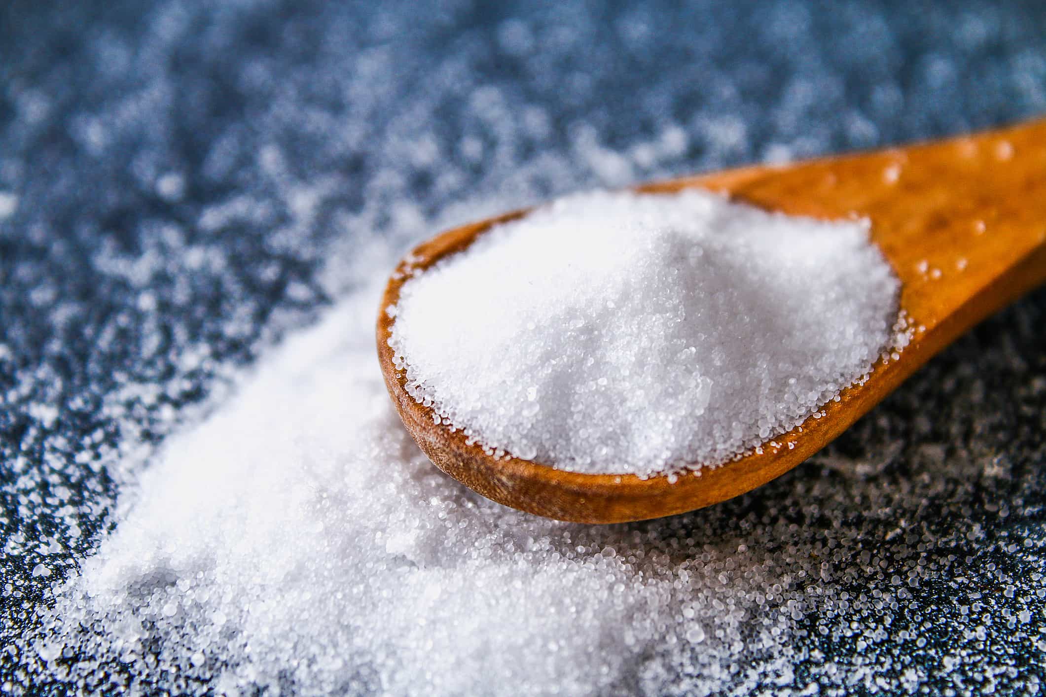 Wooden spoon overflowing with salt on a table